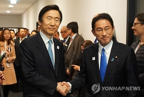 2月17日,在德国波恩,韩日外长举行会谈前在会场外握手合影。(韩联社)