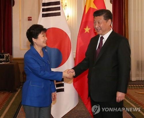 This photo, taken on April 1, 2016, shows President Park Geun-hye (L) shaking hands with Chinese President Xi Jinping before their talks on the sidelines of the Nuclear Security Summit in Washington D.C. (Yonhap)