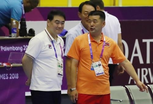 South Korean women's handball head coach Lee Kye-chung (L) speaks with a North Korean coach before the start of their teams' preliminary match at the Asian Games at GOR Popki Cibubur in Jakarta on Aug. 14, 2018. (Yonhap)