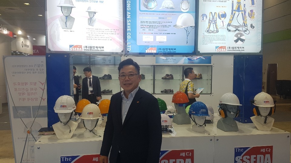 Seong An Save Co. President Kim Sang-woo poses for a photo in front of the company's safety helmet products at an exhibition event in Seoul on July 1, 2019. (Yonhap)