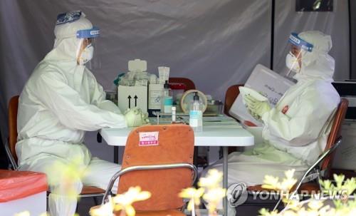 Screening station workers use ice packs to ward off the heat in Daegu on June 10, 2020, as the temperature soared above 35 C in the southeastern city. (Yonhap)