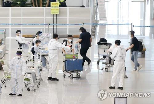 Quarantine officials attend to passengers who arrived from overseas at Incheon International Airport, west of Seoul, on May 5, 2021. South Korea has seen a steady increase in coronavirus infections in recent weeks, with the daily count reaching 676 on May 5. (Yonhap)