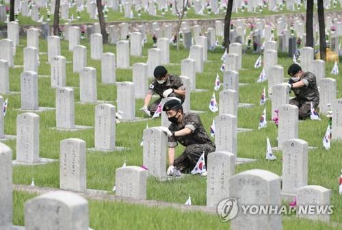 Service members clean the tombstones of South Korean soldiers who were killed during the Korean War at the national cemetery in Seoul on June 25, 2021, as the country marked the 71st anniversary of the 1950-53 war. (Yonhap)