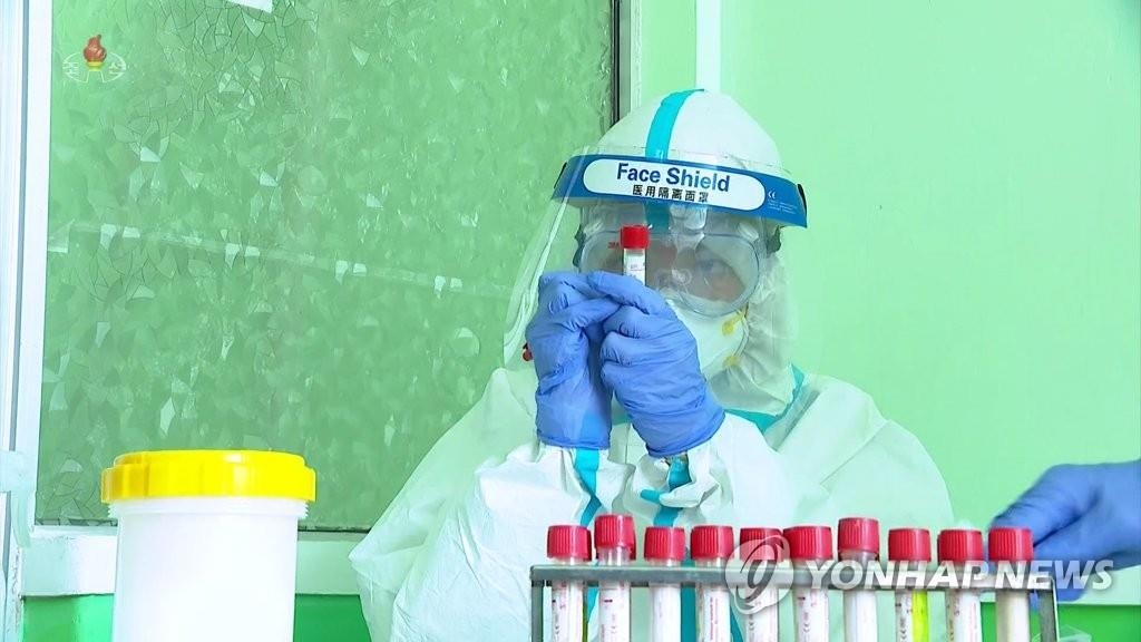 A North Korean medical worker wearing a face shield collects test samples amid a surge in suspected coronavirus cases, in this photo captured from the North's official Korean Central Television. (For Use Only in the Republic of Korea. No Redistribution) (Yonhap)