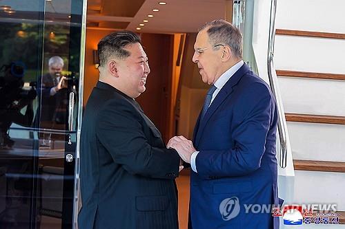 This image, published by the Korean Central News Agency on July 13, 2025, shows North Korean leader Kim Jong-un (L) and Russian Foreign Minister Sergei Lavrov holding hands during a meeting on July 12, 2025. (For Use Only in the Republic of Korea. No Redistribution) (Yonhap)