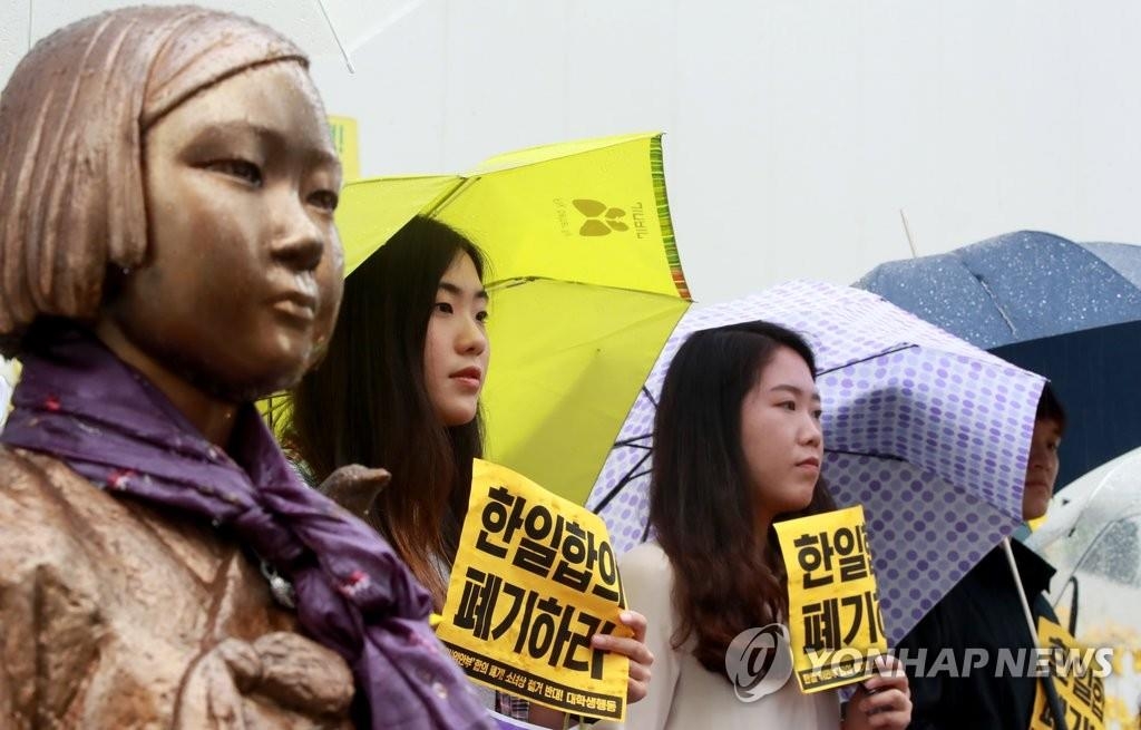 慰安婦被害者を象徴する少女像のそばで韓日合意の破棄や「和解・癒やし財団」の解散を求める人々（資料写真）＝（聯合ニュース）