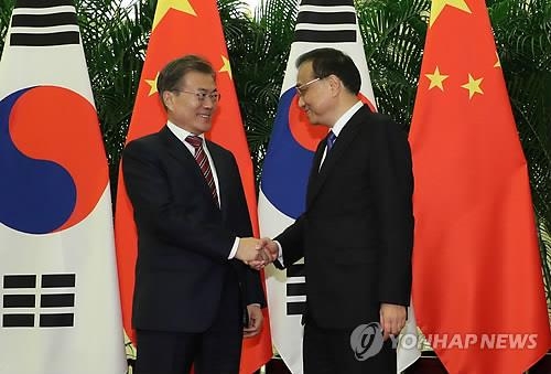 李克強首相（右）と握手する文大統領＝１５日、北京（聯合ニュース）
