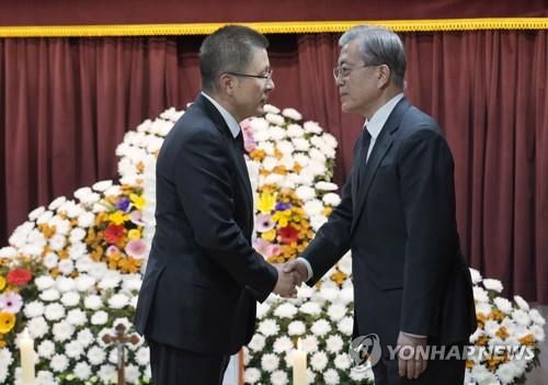 文大統領（右）が母、カン・ハンオクさんの弔問に訪れた自由韓国党の黄教安（ファン・ギョアン）代表と握手している（資料写真）＝３０日、釜山（聯合ニュース）