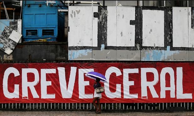 브라질 노동계가 연방하원의 연금개혁안 표결을 앞두고 파업과 시위를 예고했다. 파업을 알리는 대형 플래카드 앞을 한 주민이 지나고 있다. [브라질 뉴스포털 UOL]