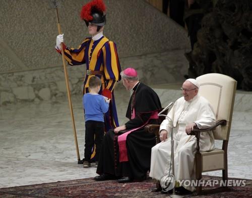 28일 바티칸에서 열린 수요 일반알현에서 6세 꼬마가 단상에 난입해 교황을 지키는 스위스 근위병의 손을 잡아당기고 있다. [AFP=연합뉴스] 