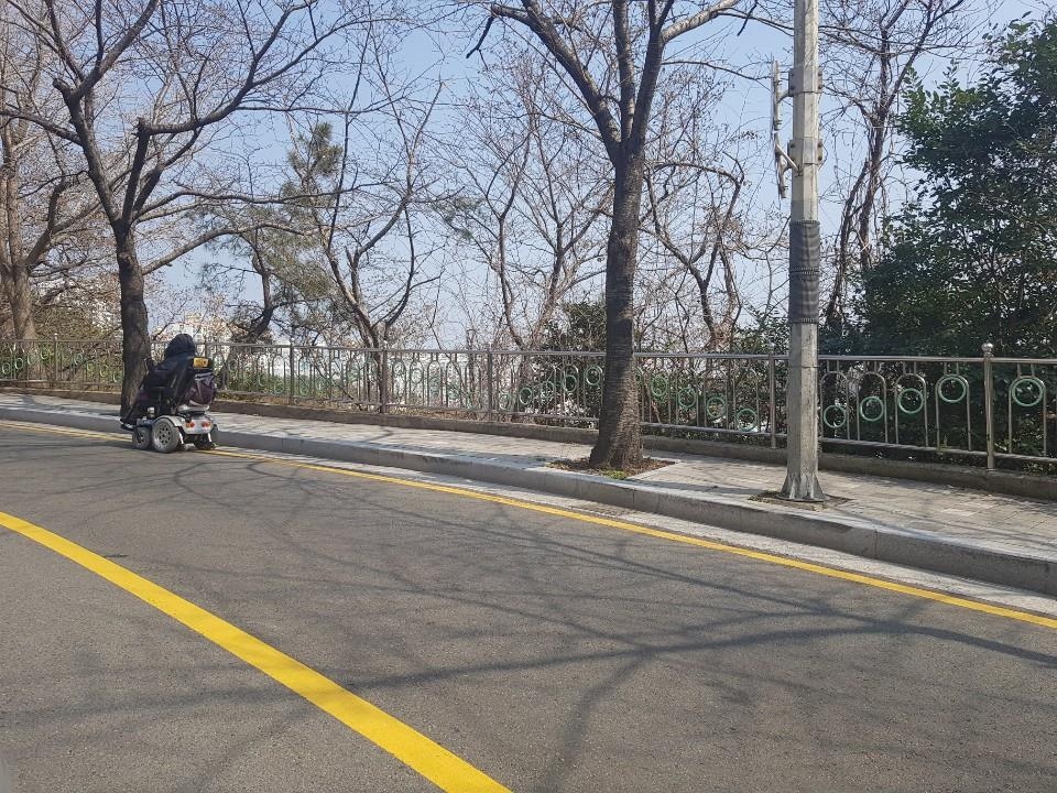 좁은 보행로에 도로로 내몰린 전동휠체어