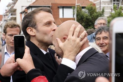 에마뉘엘 마크롱 프랑스 대통령이 26일 르 투케에서 유럽의회 선거 투표를 마치고 지지자의 이마에 키스를 하고 있다. [AP=연합뉴스] 