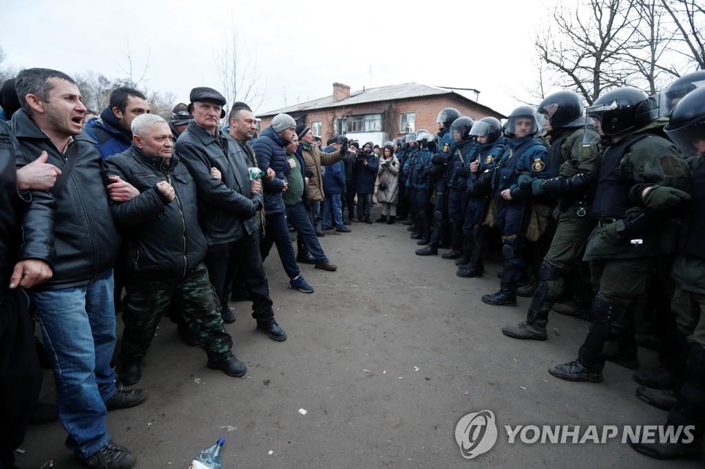 20일(현지시간) 우크라이나 폴타바주 노비예 산좌리 마을의 주민들이 중국에서 이송된 72명의 격리 수용에 반대하는 시위를 벌이며 경찰과 대치하고 있다. [로이터=연합뉴스]