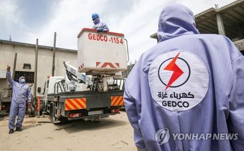 지난 4월 6일(현지시간) 팔레스타인 가자지구 남부 라파에서 전기회사 근로자들이 마스크를 쓰고 일하고 있다.[AFP=연합뉴스]