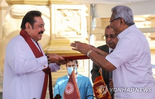 9일 스리랑카 마힌다 라자팍사 전 대통령(왼쪽)이 동생 고타바야 라자팍사 현 대통령 앞에서 선서하고 총리로 취임했다. [EPA=연합뉴스]