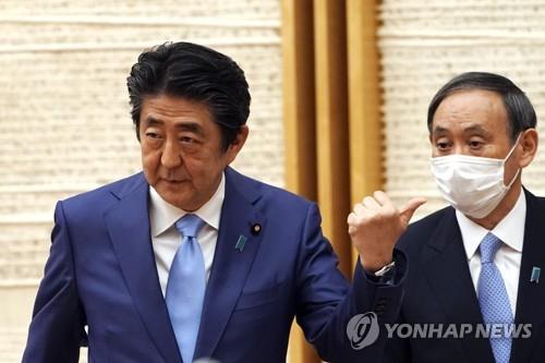2020년 5월 4일 아베 신조(왼쪽) 일본 총리가 기자회견을 마치며 몸짓을 하고 있다. 곁에 스가 요시히데 관방장관이 마스크를 쓰고 대기 중이다. [EPA=연합뉴스 자료사진]