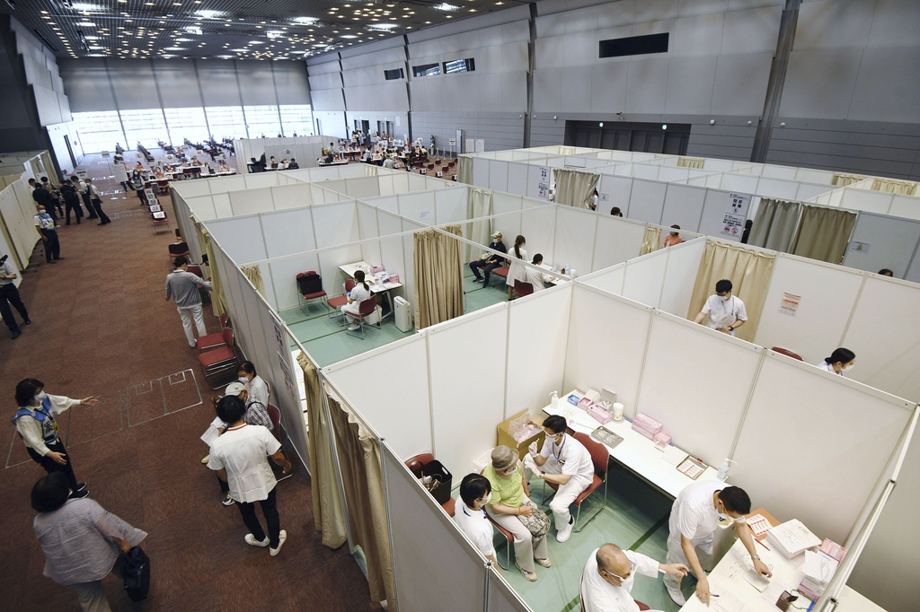 (오사카 교도=연합뉴스) 9일 일본 오사카(大阪)시에 설치된 대규모 접종센터에서 의료진이 방문자에게 신종 코로나바이러스 감염증(코로나19) 백신을 주사하고 있다.
