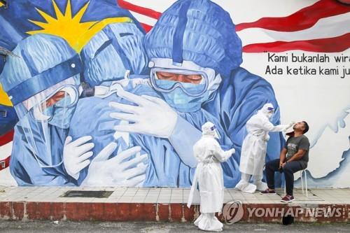 쿠알라룸푸르 벽화 앞에서 코로나19 검사하는 의료진
