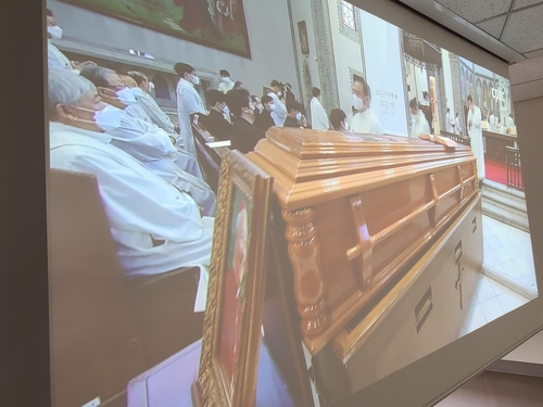 La foto, tomada el 1 de mayo de 2021, muestra una pantalla que transmite la misa fúnebre por el difunto cardenal Nicholas Cheong Jin-suk, en un edificio fuera de la catedral de Myeongdong, en Seúl.