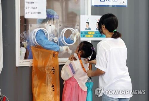 Una niña vestida con el atuendo tradicional coreano "hanbok" es sometida a un examen de coronavirus, el 21 de septiembre de 2021, en una clínica provisional en Seúl, en la festividad del Chuseok, la celebración coreana de la cosecha de otoño.