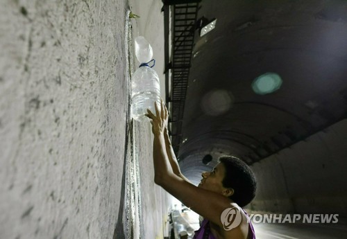 고속도로 터널에서 새는 물을 받아가는 베네수엘라 주민