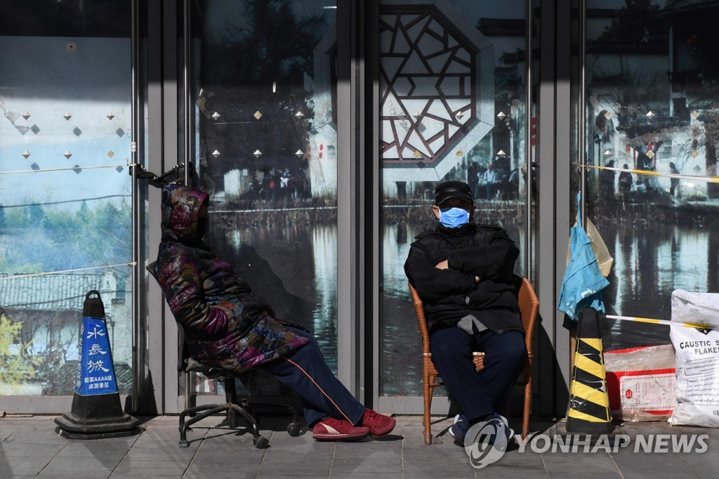 지난 16일(현지시간) 마스크를 쓴 경비원들이 문이 닫힌 중국 베이징 시내 건물 앞을 지키고 있는 모습. [AFP=연합뉴스 자료사진]