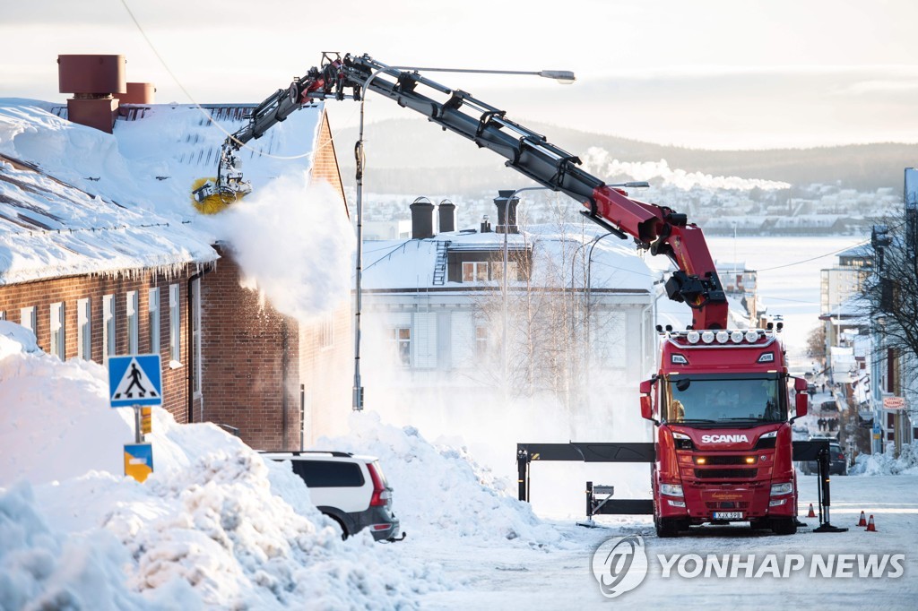26일 스웨덴 외른셸스비크의 한 주택가에서 제설 차량이 지붕 위에 쌓인 눈을 제거하고 있다.