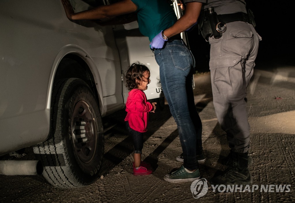 2019년 4월 11일 미국 텍사스주 맥앨런의 미국-멕시코 국경에서 온두라스 출신 불법 이민자가 미국 국경순찰대에 체포돼 신체검사를 받자 두려움에 질린 어린 딸이 울음을 터뜨리고 있다. [EPA=연합뉴스자료사진]