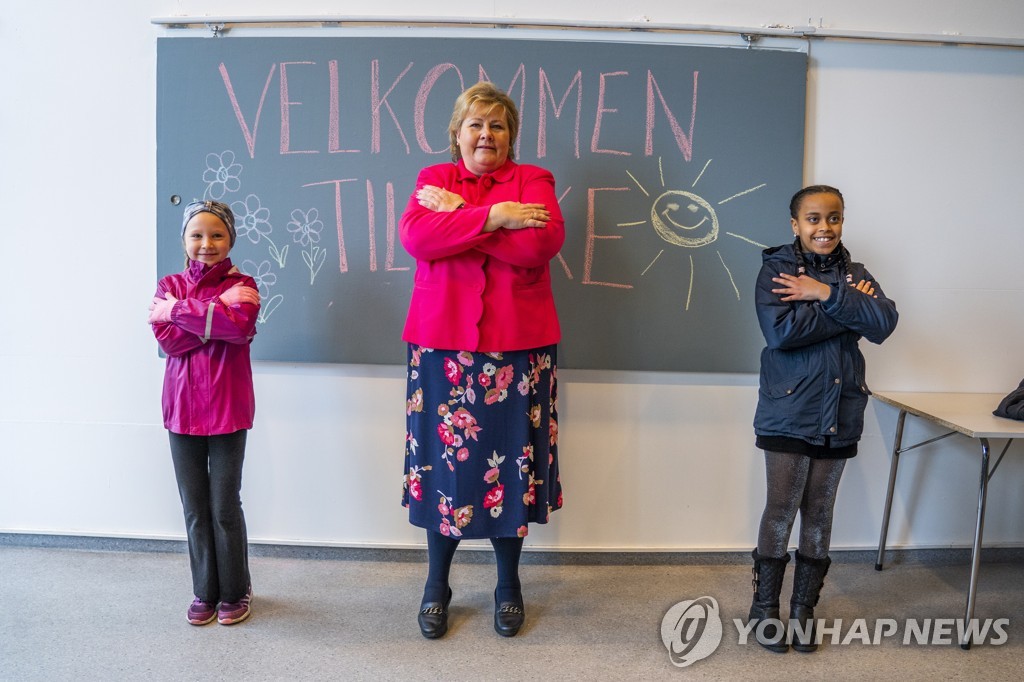 에르나 솔베르그 노르웨이 총리(가운데)가 27일(현지시간) 개학한 노르웨이 오슬로의 한 초등학교를 찾아 학생들로부터 인사법을 배우고 있다. [EPA/Hakon Mosvold Larsen=연합뉴스]