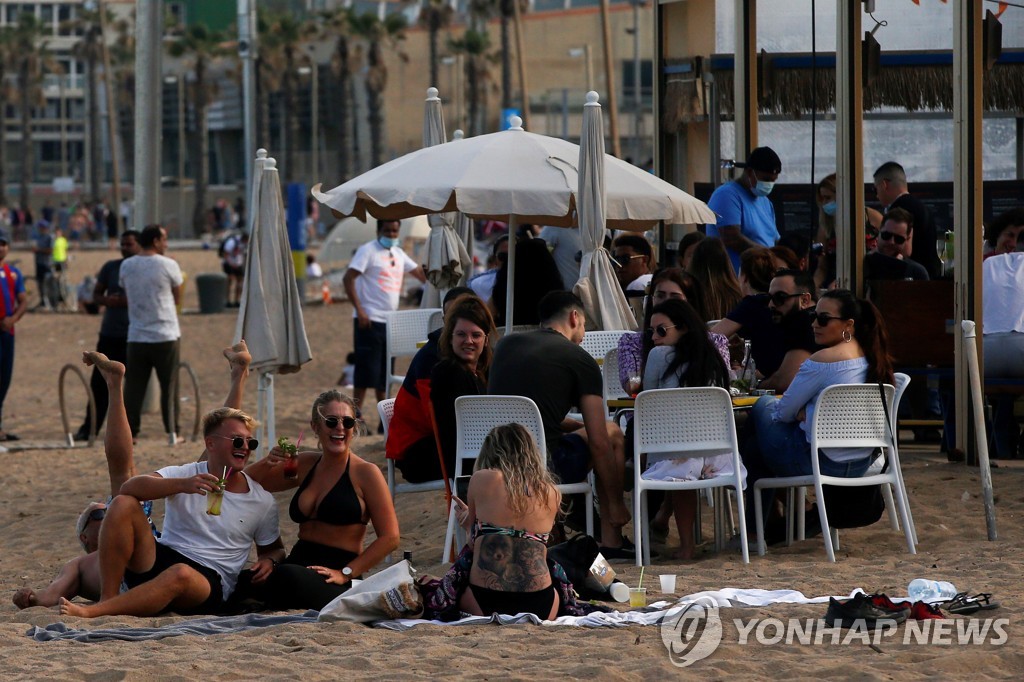 지난달 31일 스페인 바르셀로나의 한 해변에서 시민들이 일상을 즐기고 있다. [EPA=연합뉴스 자료사진]