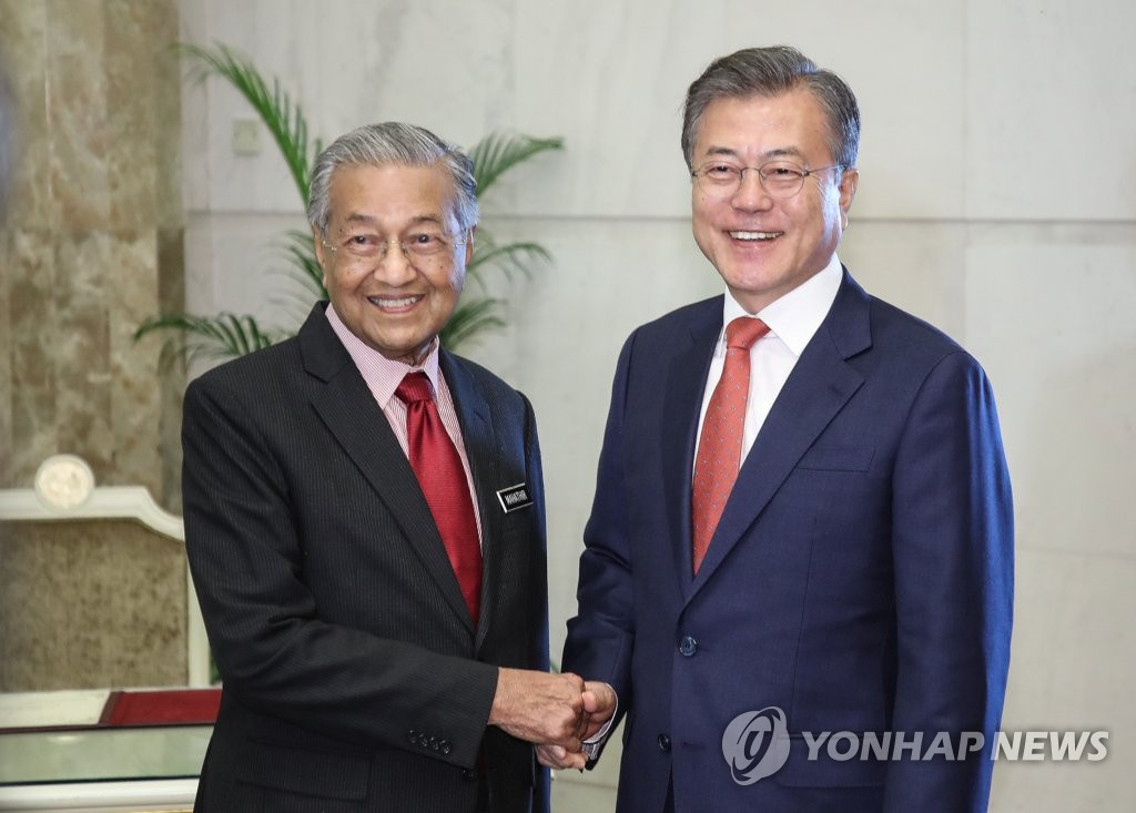 South Korean President Moon Jae-in (R) and Malaysian Prime Minister Mahathir Mohamad shake hands before holding summit talks at the Malaysian leader's office in Putrajaya, the federal administrative capital near Kuala Lumpur, on March 13, 2019. (Yonhap)