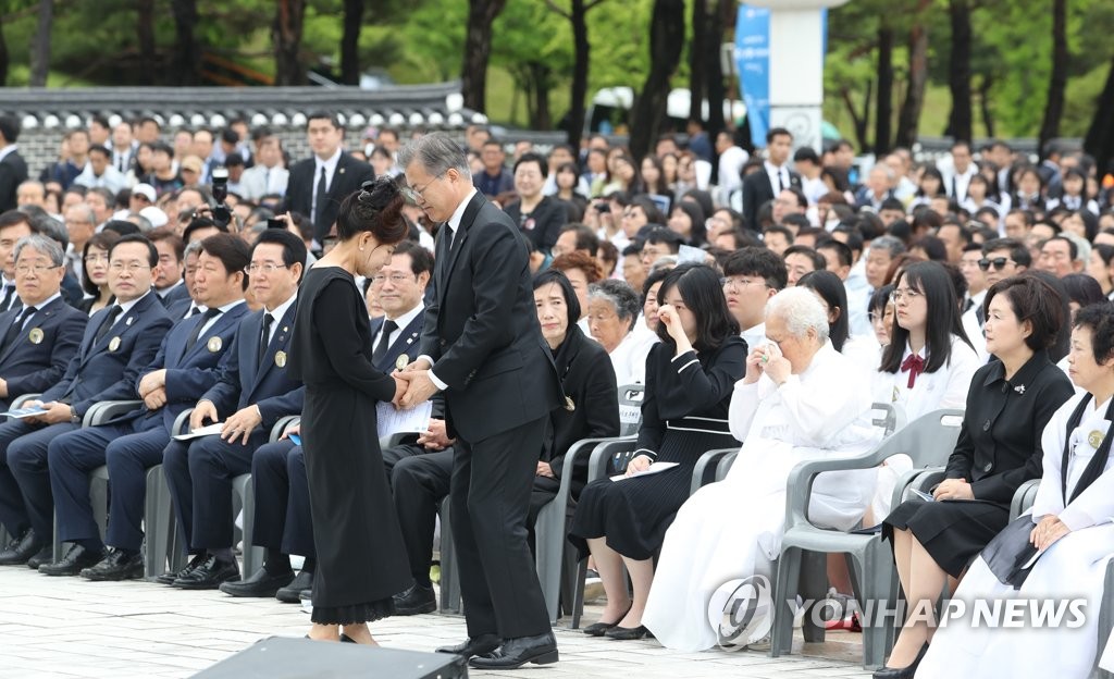 President Moon Jae-in holds the hands of a participant in the 1980 pro-democracy uprising during an anniversary ceremony held at the National Cemetery for the May 18th Democratic Uprising in Gwangju on May 18, 2019. (Yonhap)