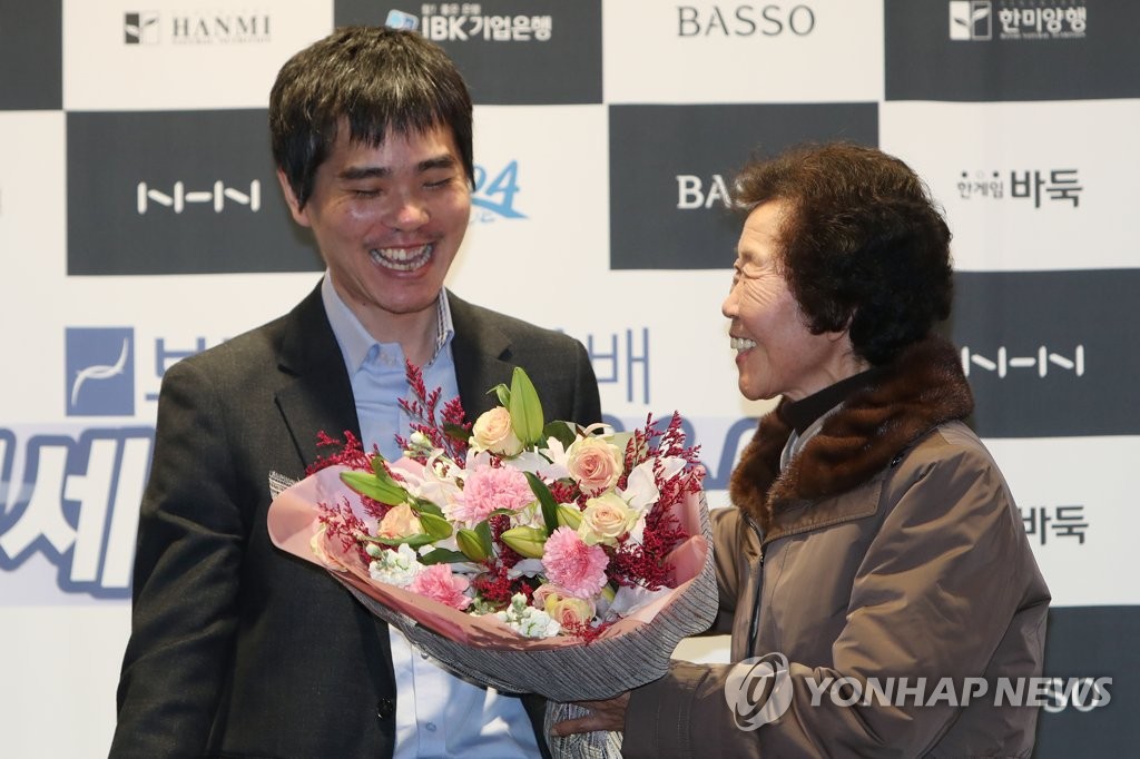 South Korean Go player Lee Se-dol (L) receives a bouquet of flowers from his mother, Park Yang-rye, after his retirement match against artificial intelligence program HanDol at El Dorado Resort in Sinan, 400 kilometers south of Seoul, on Dec. 21, 2019. (Yonhap)