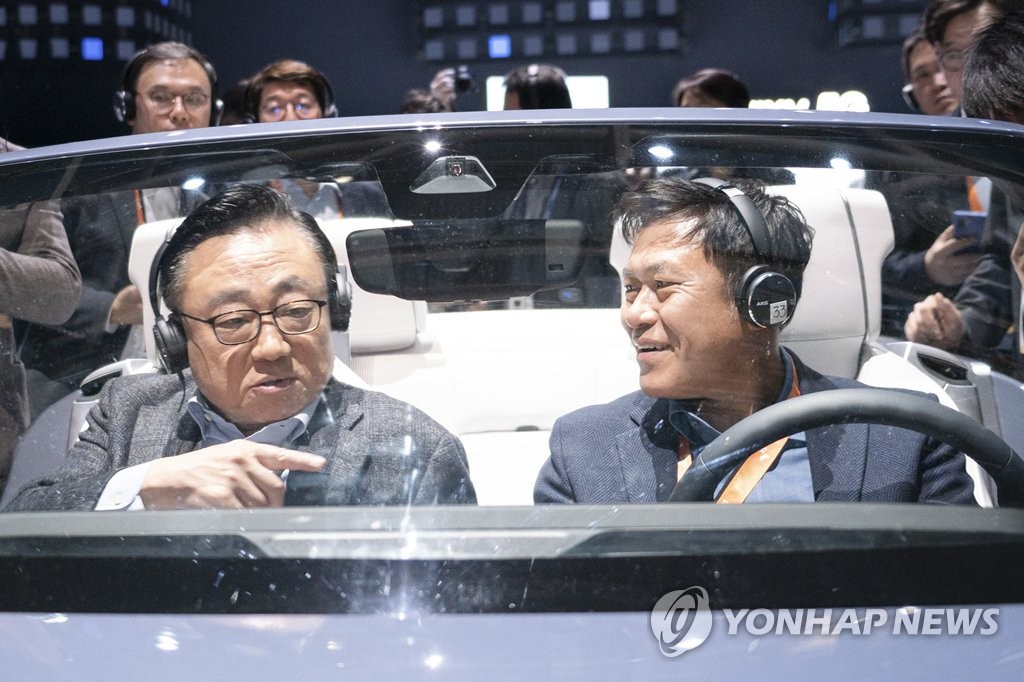 In this photo provided by SK Telecom Co. on Jan. 7, 2020, SK Telecom CEO Park Jung-ho (R) speaks with Koh Dong-jin, president and CEO of Samsung Electronics' mobile business division, at a digital cockpit made by Samsung at the company's Consumer Electronics Show (CES) booth in Las Vegas, Nevada. (PHOTO NOT FOR SALE) (Yonhap)