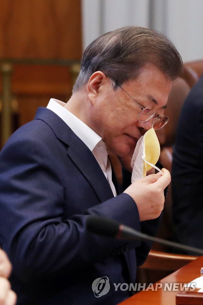 President Moon Jae-in takes his face mask off before making opening remarks at an emergency economic council meeting at Cheong Wa Dae in Seoul on March 19, 2020. (Yonhap)