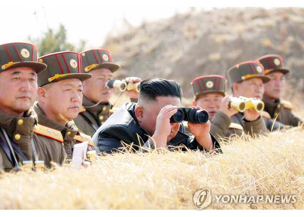 This photo released on March 21, 2020 by the Rodong Sinmun, the North's official newspaper, shows Kim Jong-un (C) watch through binoculars an artillery fire competition held a day earlier. (For Use Only in the Republic of Korea. No Redistribution) (Yonhap)