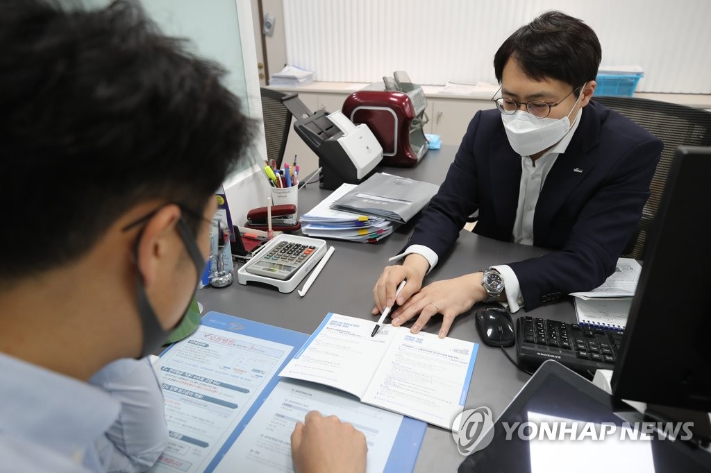 In this photo, taken April 6, 2020, a local customer (L) is seen having an interview with a bank official in Seoul for a special, low-interest loan for businesses hit by the COVID-19 pandemic. (Yonhap)