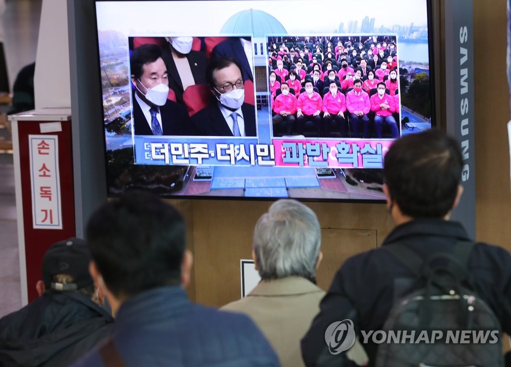 In this file photo taken April 15, 2020, citizens watch a television news report on the results of the 21st parliamentary elections at Seoul Station in the capital city. (Yonhap)