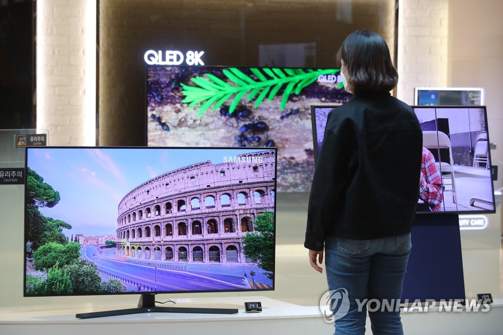 This file photo taken April 29, 2020, shows a customer looking at Samsung Electronics Co.'s QLED TVs at a store in Seoul. (Yonhap)
