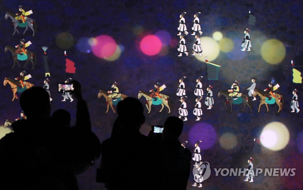 In this file photo, spectators watch the changing of colorful images projected onto a panoramic screen that is part of the Immersive Digital Gallery during its opening event held at the National Museum of Korea in Seoul on May 19, 2020. (Yonhap)