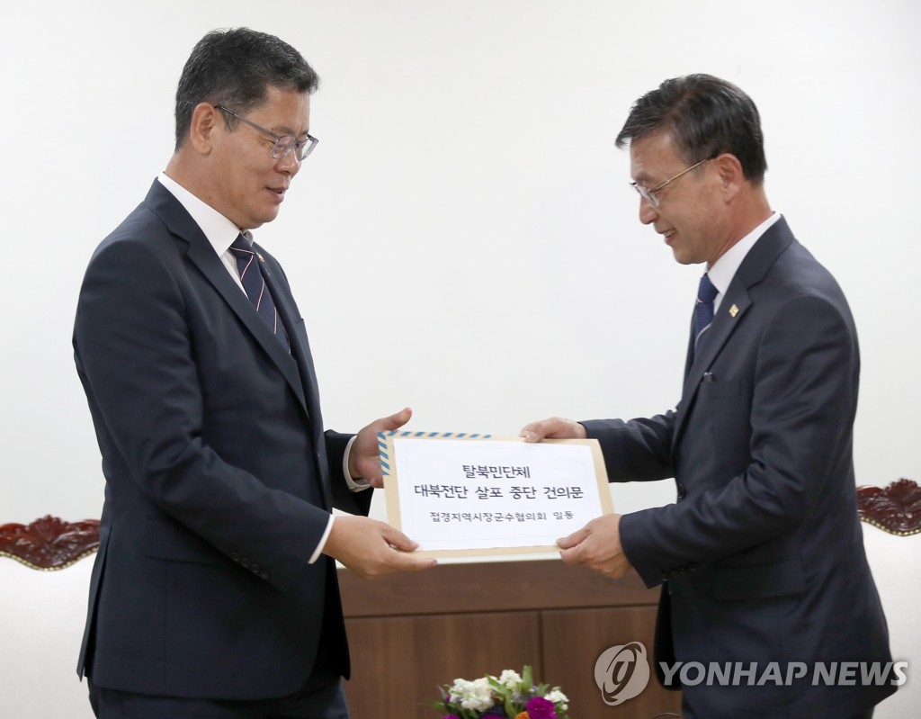 Unification Minister Kim Yeon-chul (L) receives a letter from Jung Ha-young, mayor of Gimpo, calling for stricter regulations to stop defector groups from flying leaflets into North Korea, on June 5, 2020. (Yonhap)