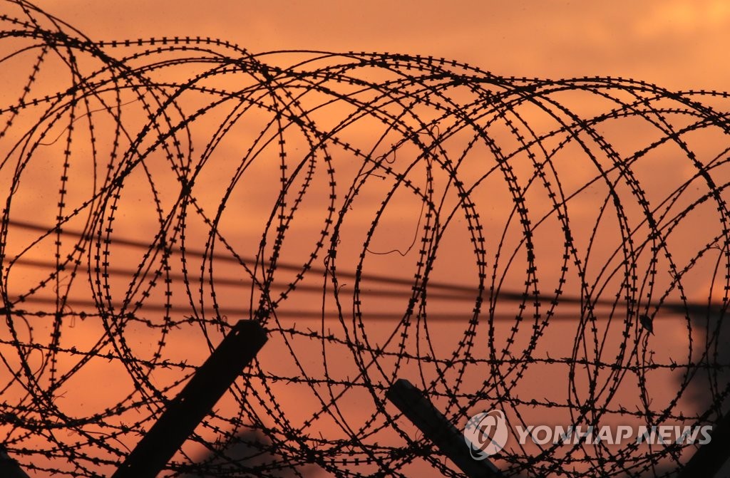 철조망 뒤로 지는 해