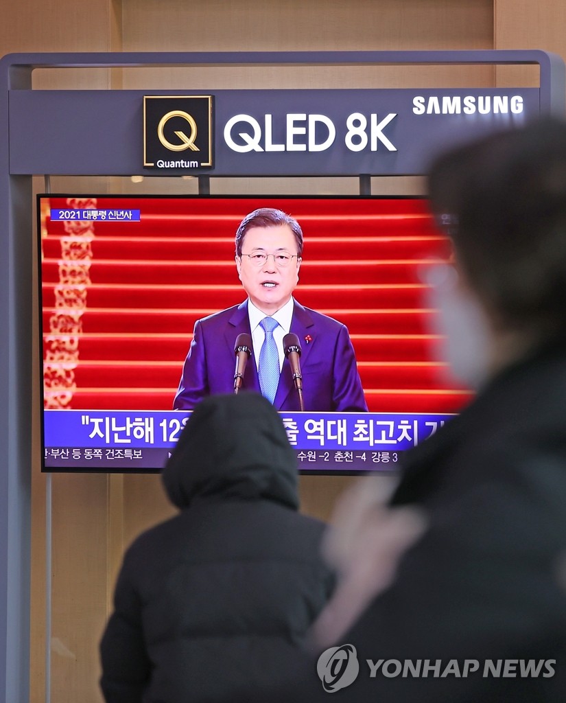 People watch a TV report of President Moon Jae-in delivering a New Year's address at Seoul Station on Jan. 11, 2021. In the televised address, Moon said the government will provide all South Koreans with free-of-charge COVID-19 vaccines in phases starting next month. (Yonhap)