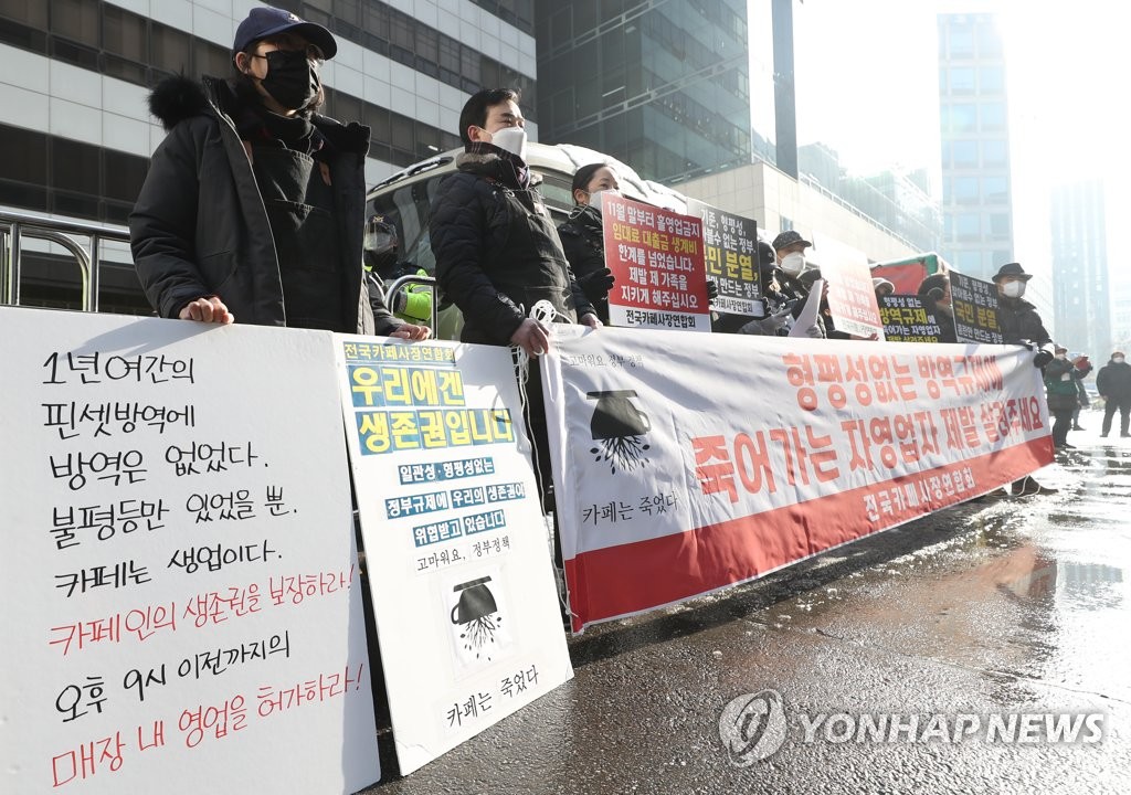 Member of a cafe owners' association demand the lifting of COVID-19 business restrictions during a rally outside the ruling Democratic Party's headquarters in Seoul on Jan. 13, 2021. (Yonhap)