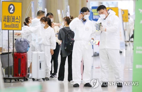 Des employés sanitaires guident des passagers dans un hall d'arrivée de l'aéroport international d'Incheon le dimanche 5 septembre 2021.