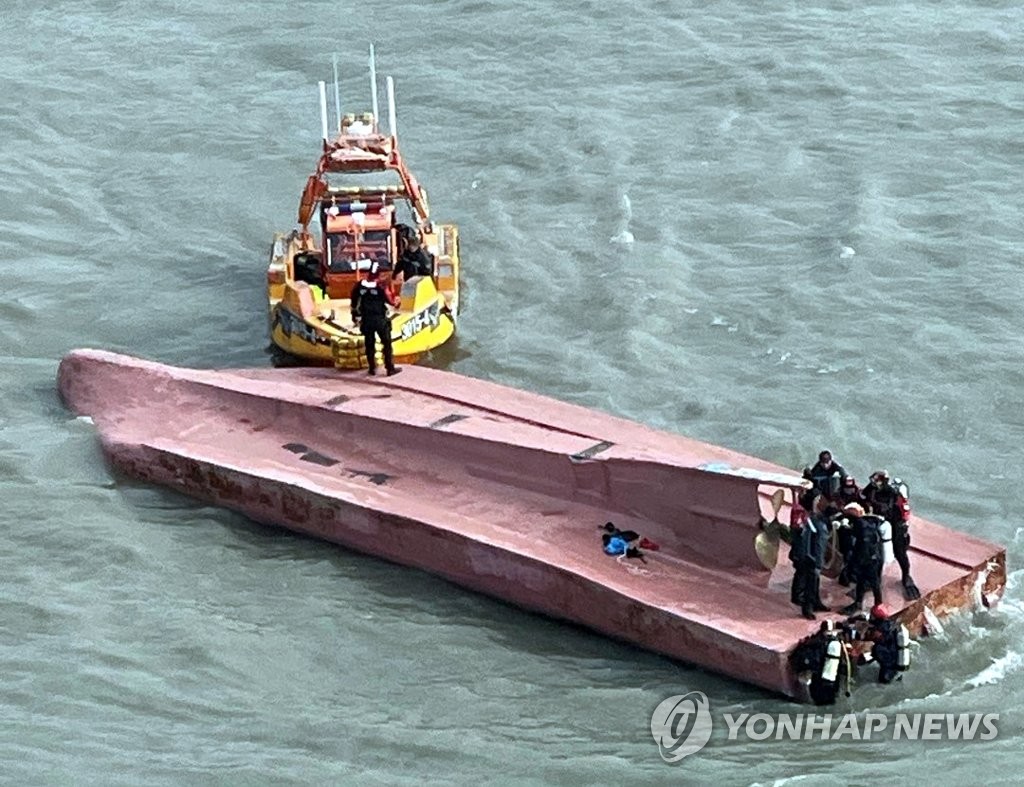 This photo provided by the Coast Guard shows rescue officials working to save seafarers from a capsized fishing boat in waters off the country's southwestern coast near Jin Island on Jan. 8, 2022. (PHOTO NOT FOR SALE) (Yonhap)