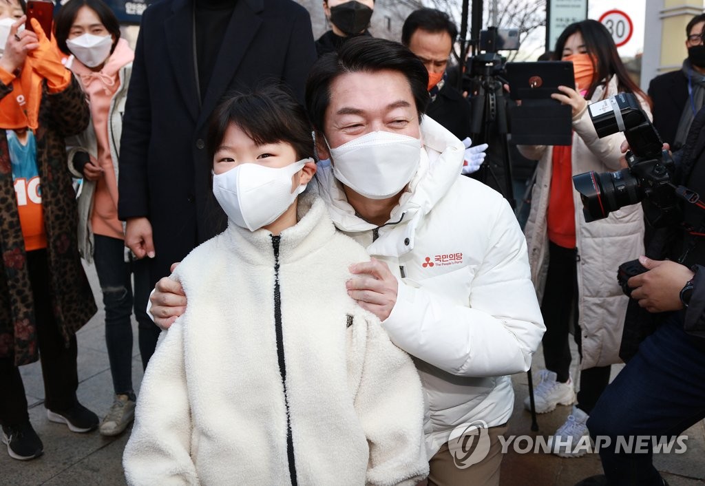 Ahn Cheol-soo, the presidential candidate of the centrist People's Party, poses with a child near a train station in Daegu on Feb. 15, 2022. (Yonhap)