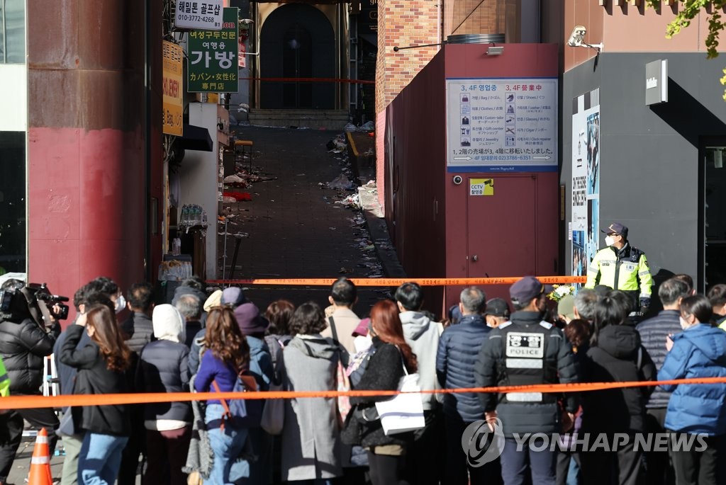 Des gens regardent le 4 novembre 2022 le lieu de la bousculade du 29 octobre dans le quartier d'Itaewon à Séoul.