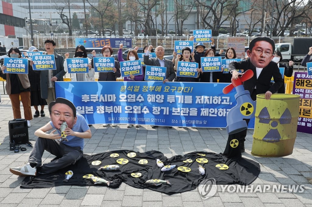 Protestors wear masks of South Korean President Yoon Suk Yeol (L) and Japanese Prime Minister Fumio Kishida (R) as members of civic groups take part in a protest rally near the presidential office in Seoul on March 10, 2023, to call for the government to urge that Japan not release water containing radioactive materials into the sea from the crippled Fukushima nuclear power plant. (Yonhap)