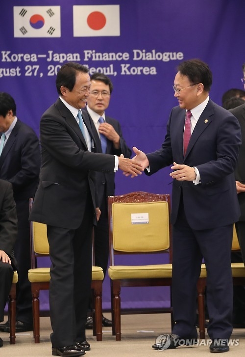 South Korea's Finance Minister Yoo Il-ho (R) shakes hands with his Japanese counterpart Taro Aso at the Korea-Japan finance ministers meeting in Seoul on Aug. 27, 2016. (Yonhap file photo)